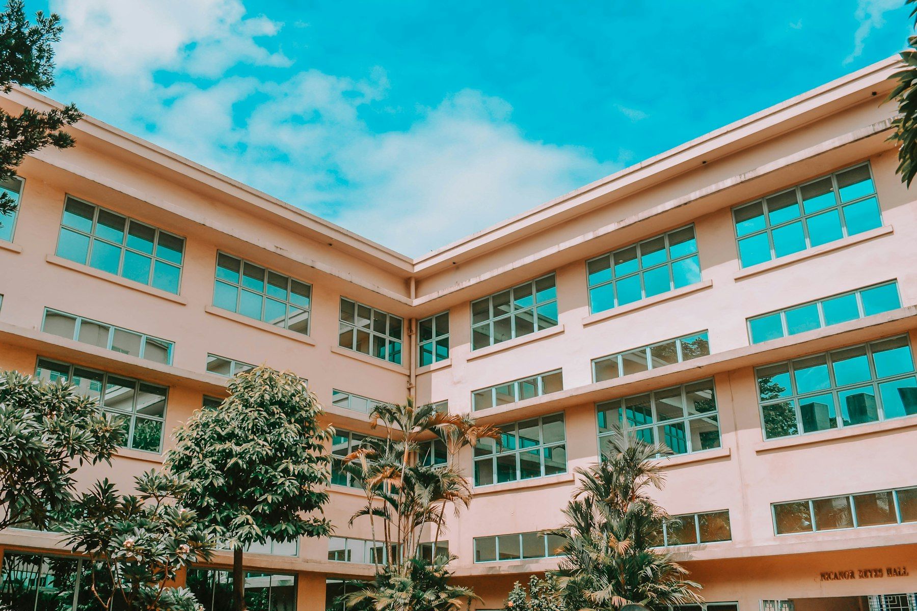 Fachada de um prédio escolar com jardim e céu azul